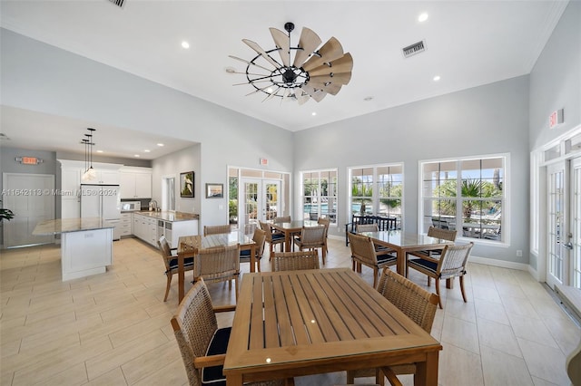 dining room featuring a towering ceiling, french doors, and sink