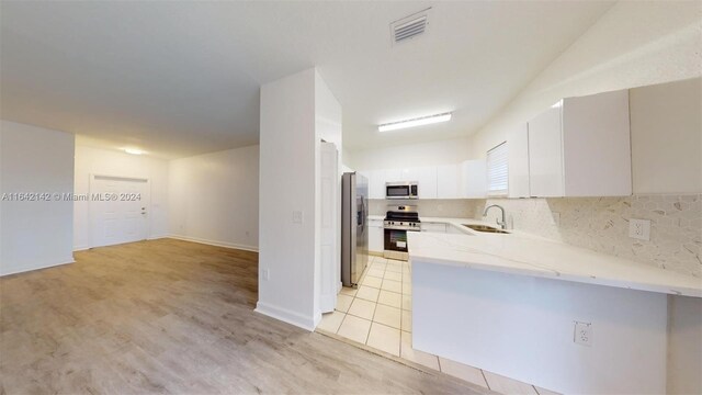 kitchen with stainless steel appliances, backsplash, light stone countertops, white cabinetry, and light hardwood / wood-style flooring