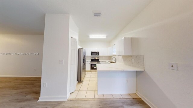 kitchen with decorative backsplash, light wood-type flooring, stainless steel appliances, and white cabinetry