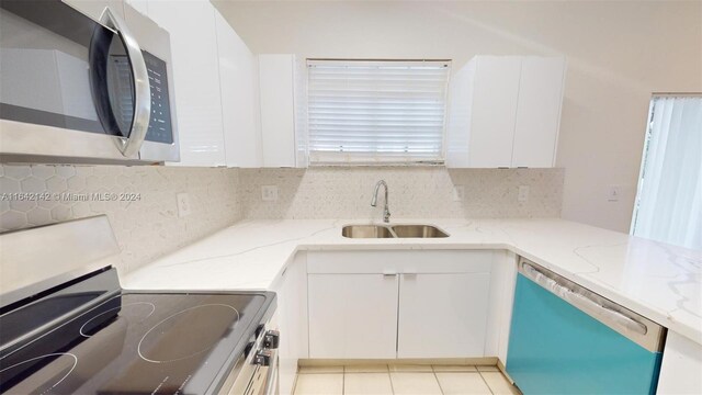 kitchen featuring light stone counters, stainless steel appliances, sink, and white cabinetry