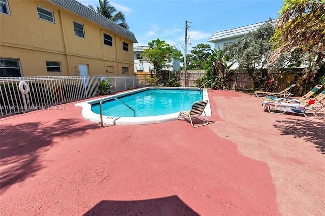 community pool with a fenced backyard and a patio