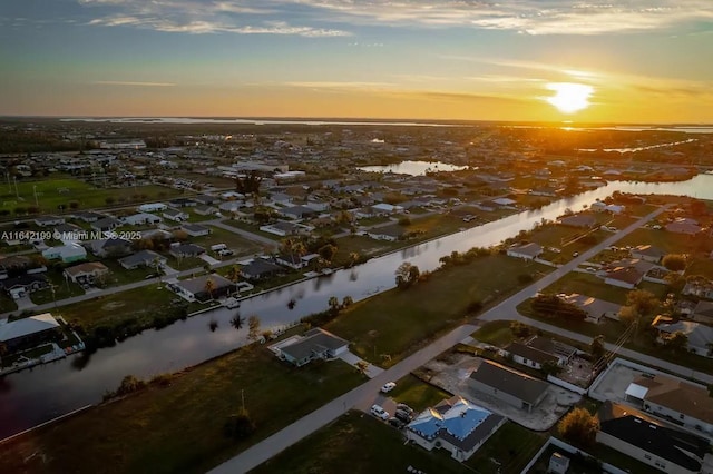 aerial view at dusk featuring a water view