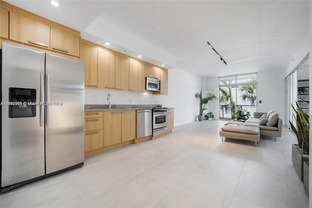 kitchen featuring stone counters, light brown cabinetry, appliances with stainless steel finishes, light tile patterned floors, and sink