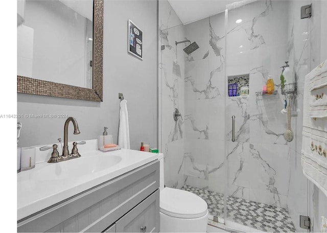 bathroom featuring a shower with door, toilet, and vanity