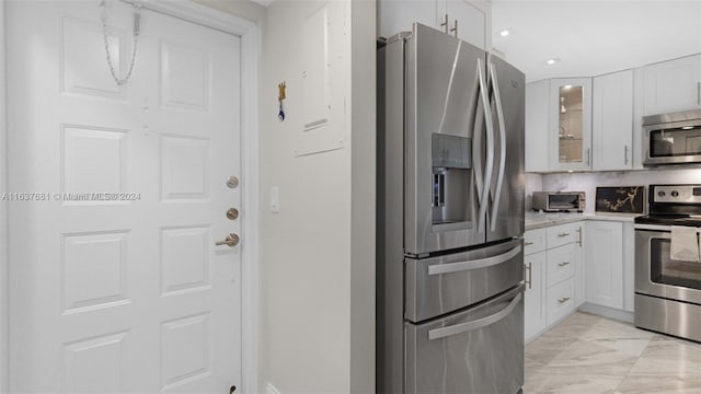 kitchen with white cabinets, appliances with stainless steel finishes, light countertops, and glass insert cabinets