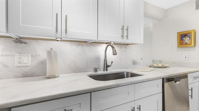 kitchen with light stone counters, a sink, white cabinets, dishwasher, and backsplash