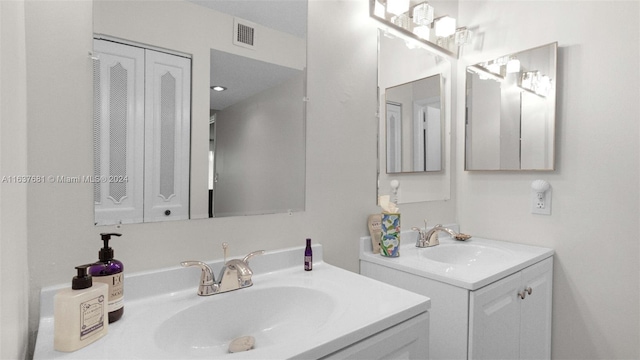 bathroom with a sink, visible vents, and two vanities