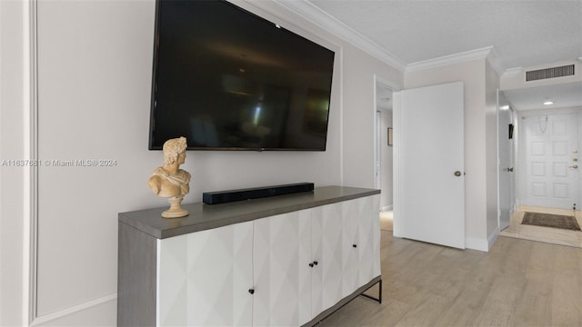 hall featuring light wood-type flooring, visible vents, a textured ceiling, crown molding, and baseboards