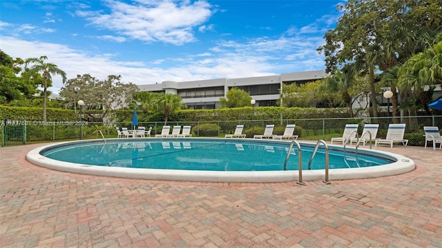 pool with a patio area and fence