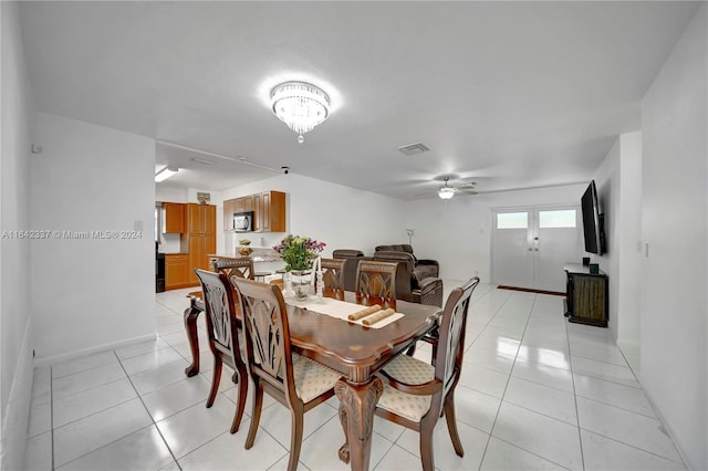 tiled dining area featuring ceiling fan with notable chandelier