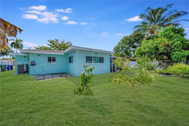 rear view of property with central AC and a yard