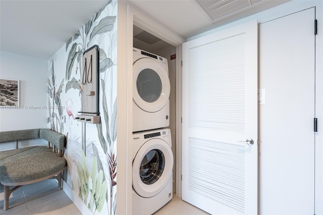 laundry area with light tile patterned floors and stacked washer and dryer