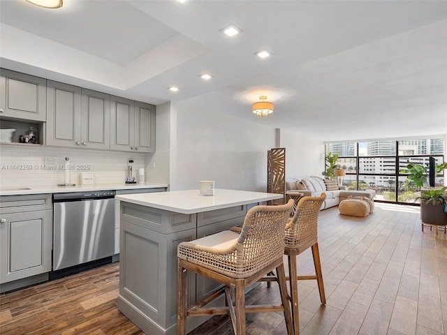 kitchen featuring stainless steel dishwasher, a kitchen breakfast bar, a center island, and gray cabinets