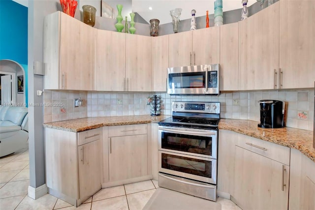 kitchen featuring light stone countertops, light brown cabinetry, and stainless steel appliances