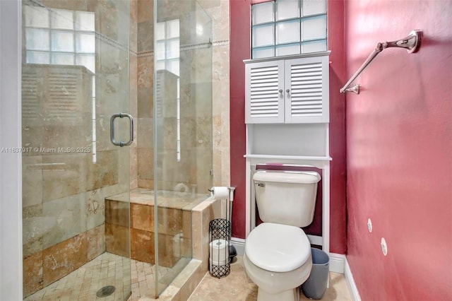 bathroom featuring a shower with door and toilet