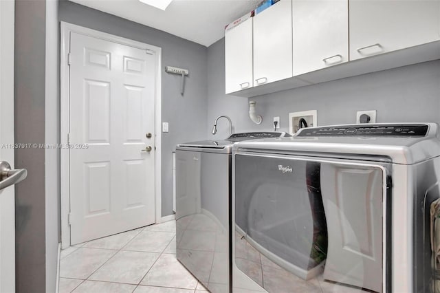 clothes washing area with cabinets, independent washer and dryer, and light tile patterned floors