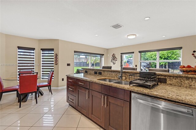 kitchen with light tile patterned floors, sink, dishwasher, and light stone countertops