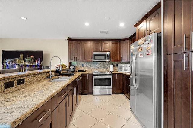 kitchen featuring light stone counters, light tile patterned flooring, backsplash, stainless steel appliances, and sink