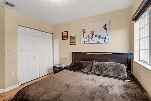 bedroom with a textured ceiling, hardwood / wood-style flooring, and a closet