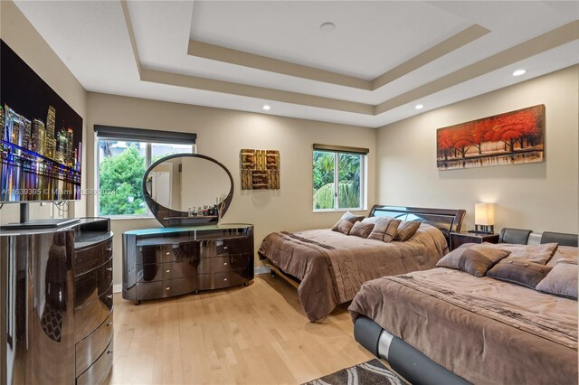 bedroom featuring a raised ceiling and light hardwood / wood-style floors