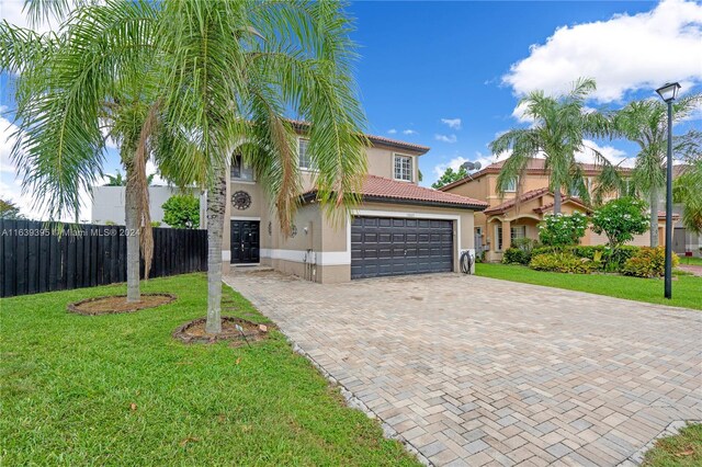 mediterranean / spanish home featuring a front lawn and a garage