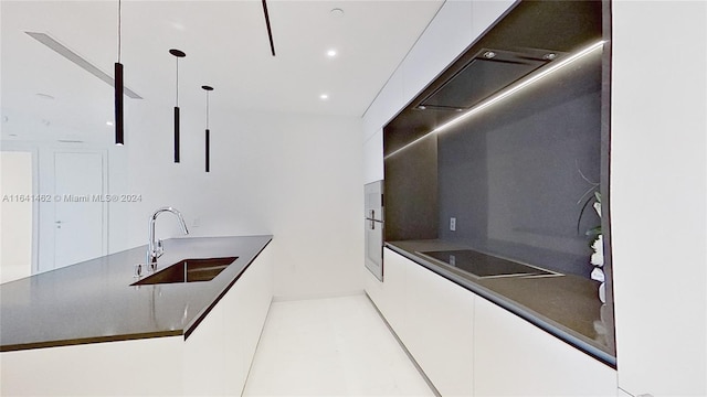 kitchen featuring cooktop, sink, pendant lighting, and white cabinets