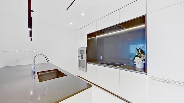 kitchen with white oven, sink, black electric cooktop, and white cabinets