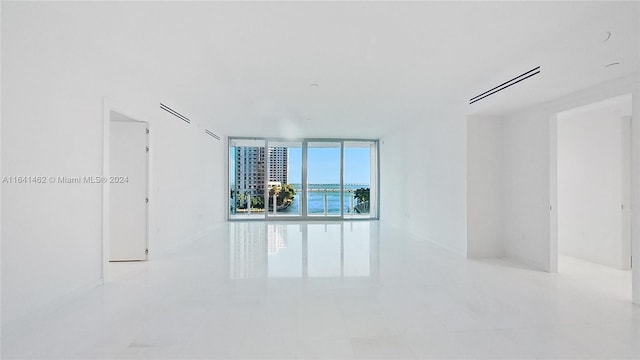 unfurnished room with a water view and light tile patterned floors