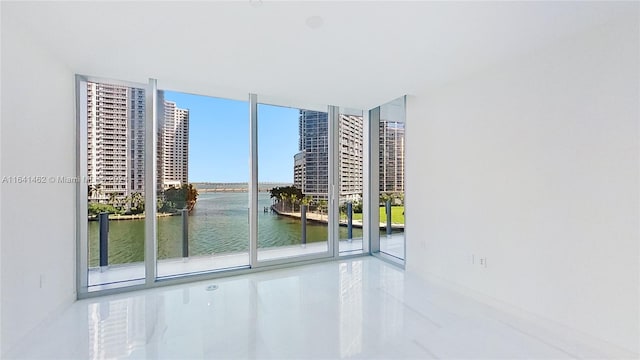 unfurnished room featuring a water view, a healthy amount of sunlight, and a wall of windows