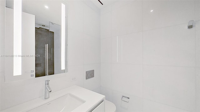 bathroom featuring toilet, vanity, and tile walls