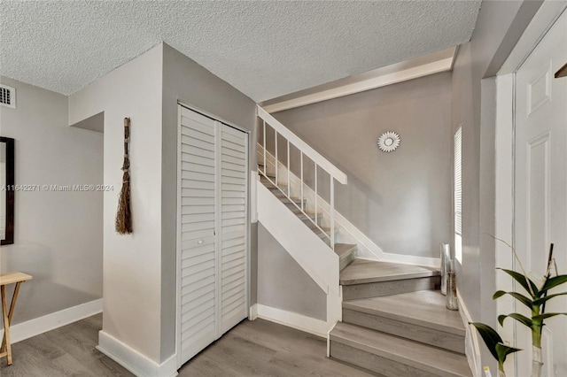 stairs with a textured ceiling and hardwood / wood-style flooring