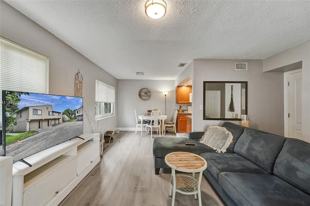 living room with light wood-type flooring and a textured ceiling