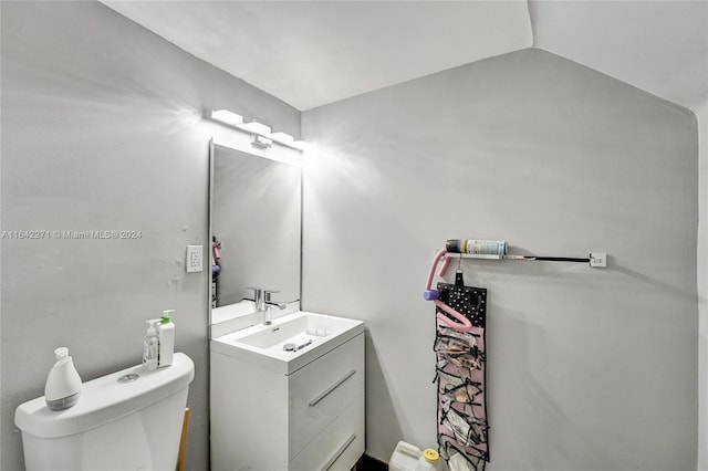 bathroom featuring toilet, vanity, and lofted ceiling