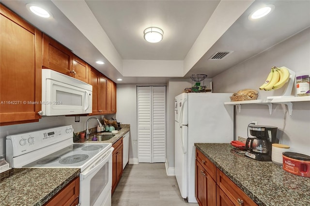 kitchen featuring dark stone countertops, white appliances, sink, and light hardwood / wood-style floors