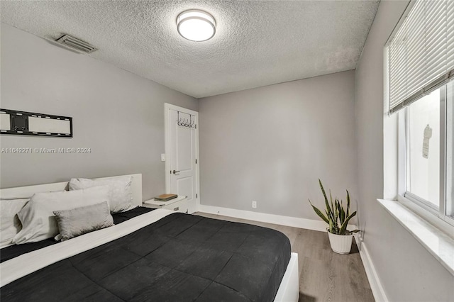 bedroom featuring hardwood / wood-style floors and a textured ceiling