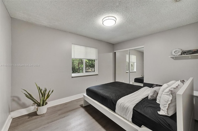 bedroom with hardwood / wood-style flooring, a textured ceiling, and a closet