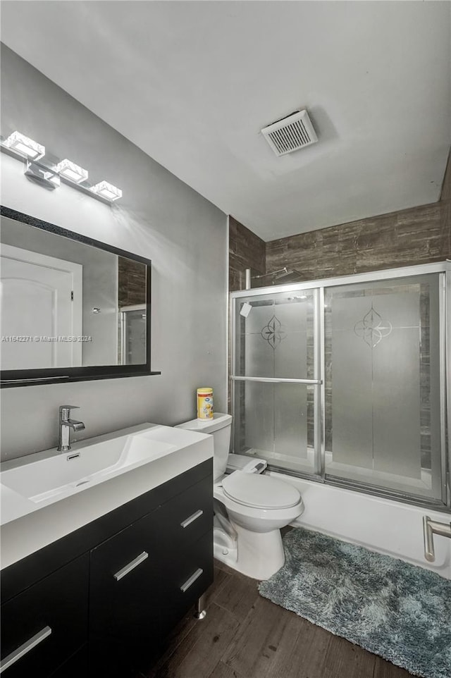 full bathroom with shower / bath combination with glass door, toilet, vanity, and hardwood / wood-style floors