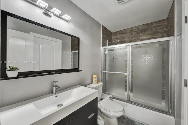 full bathroom featuring combined bath / shower with glass door, vanity, and toilet