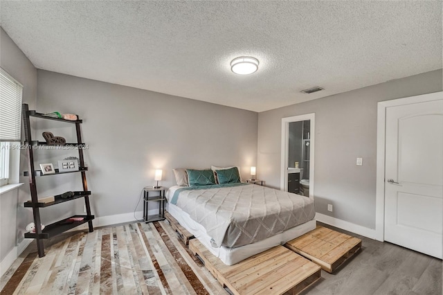 bedroom with a textured ceiling, hardwood / wood-style floors, and ensuite bathroom