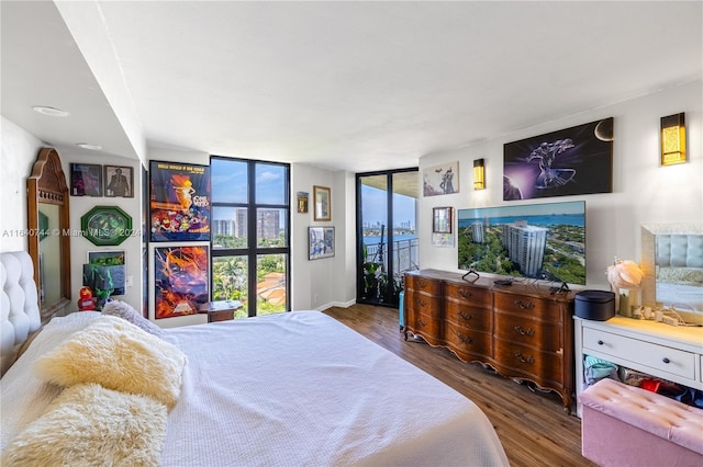 bedroom featuring floor to ceiling windows, access to exterior, and hardwood / wood-style flooring