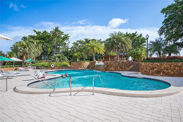 view of swimming pool with pool water feature and a patio