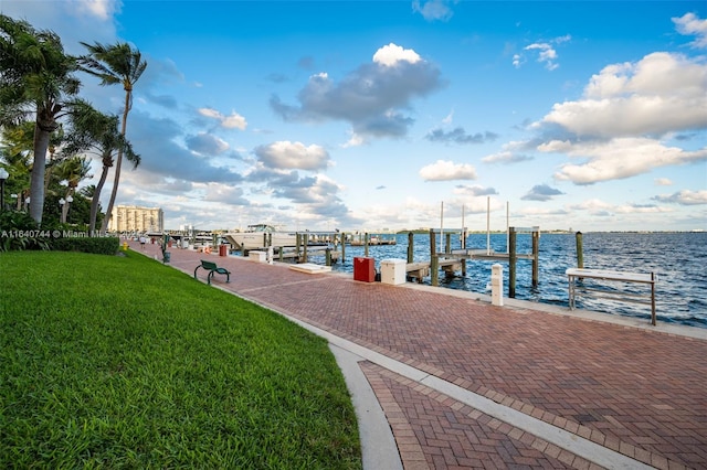 view of dock with a water view and a lawn