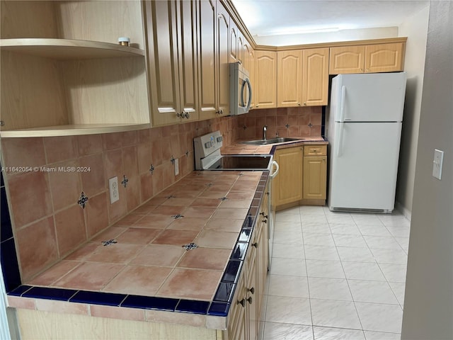 kitchen with white refrigerator, light tile patterned floors, tasteful backsplash, sink, and tile countertops