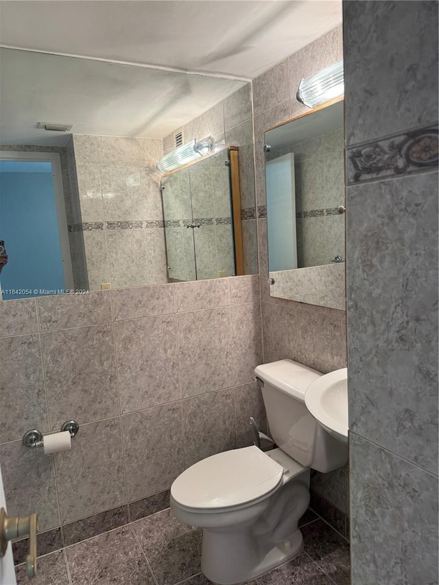 bathroom featuring tile walls, tile patterned floors, and toilet