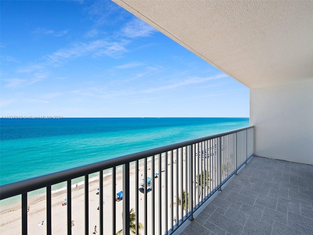 balcony featuring a view of the beach and a water view