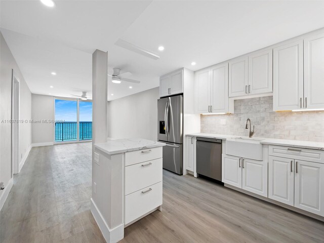 kitchen featuring light hardwood / wood-style flooring, ceiling fan, white cabinetry, appliances with stainless steel finishes, and sink