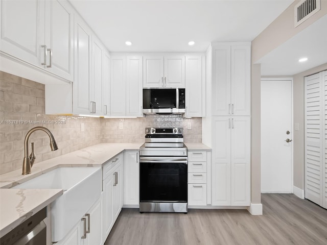 kitchen featuring light stone counters, white cabinets, stainless steel appliances, and light hardwood / wood-style floors