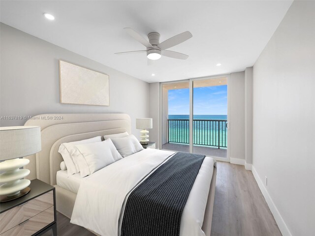 bedroom featuring light hardwood / wood-style flooring, a wall of windows, ceiling fan, access to outside, and a water view