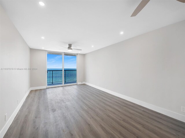 unfurnished room featuring ceiling fan, expansive windows, and wood-type flooring