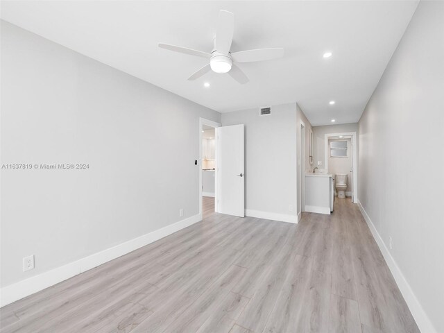 unfurnished bedroom with ceiling fan, sink, light wood-type flooring, and ensuite bath